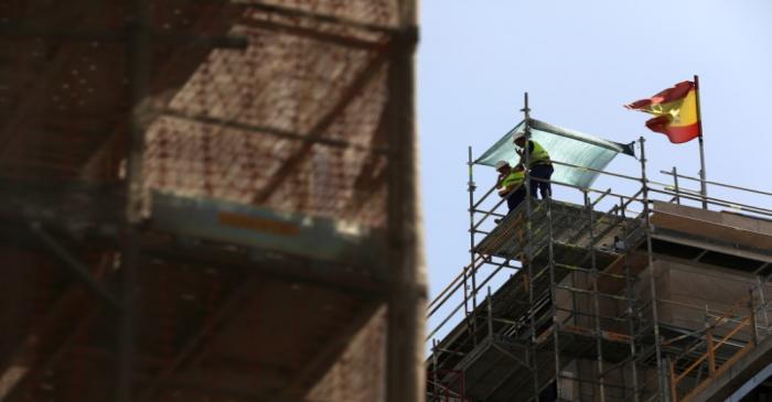 Workers stand next to a Spanish flag at a construction site in Madrid