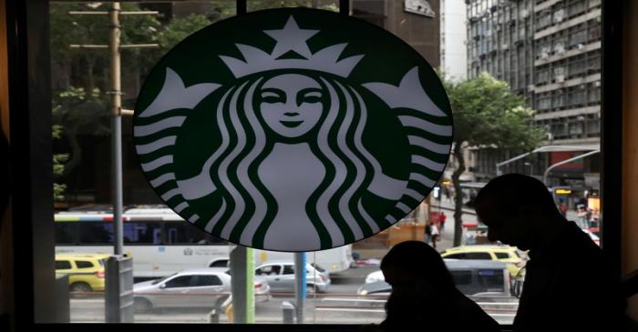 Customers pass by the logo of an American coffee company Starbucks inside a coffee shop in Rio