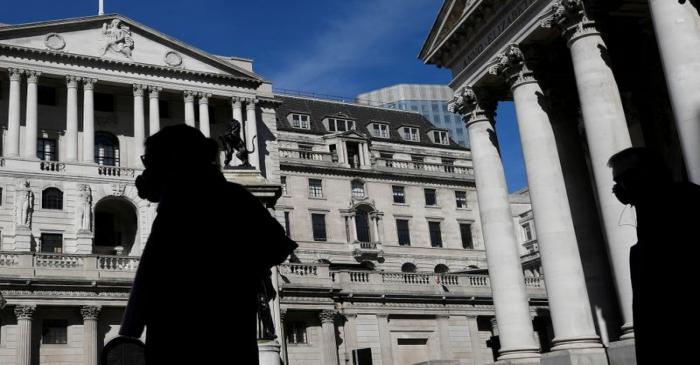 FILE PHOTO: People wearing masks walk past the Bank of England