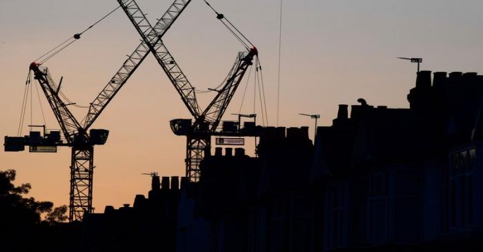 Construction cranes are seen on a residential building project behind homes in west London in