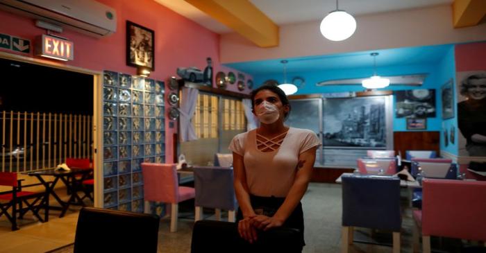 FILE PHOTO: A waitress watches the TV as she waits for costumers in a restaurant, following the