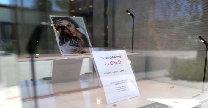 The window display of a retail store shows a closed sign as the global outbreak of the