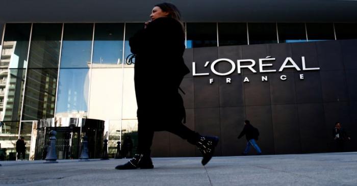 FILE PHOTO: A woman walks by the logo of French cosmetics group L'Oreal in the western Paris