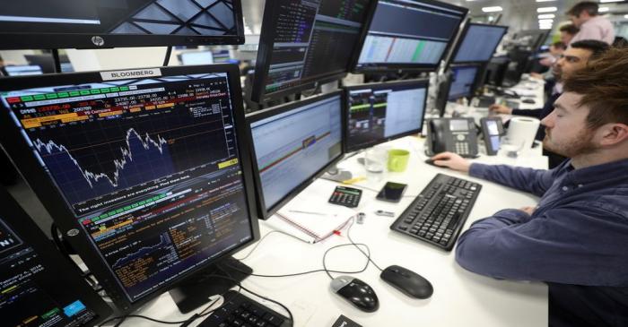 FILE PHOTO: Traders looks at financial information on computer screens on the IG Index trading