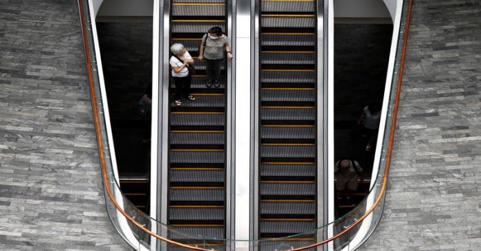A woman wearing a mask in precaution of the coronavirus outbreak takes the escalator at a mall