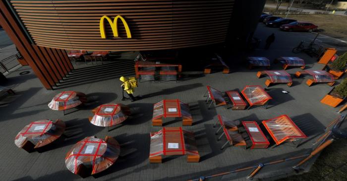 FILE PHOTO: Food delivery courier rides a scooter among plastic-wrapped tables of McDonald's
