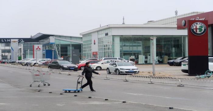 FILE PHOTO: Woman wearing a face mask pulls a trolley as she crosses the road near showrooms of