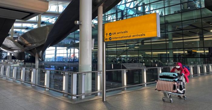 FILE PHOTO: An air passenger pushes luggage at Heathrow Airport in London