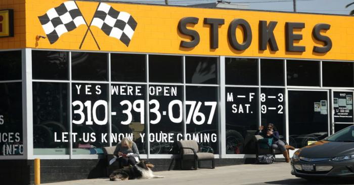 People wait outside a newly-reopened tire store, as the global outbreak of the coronavirus