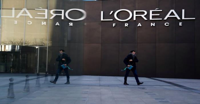 FILE PHOTO: A man walks by the logo of French cosmetics group L'Oreal in the western Paris