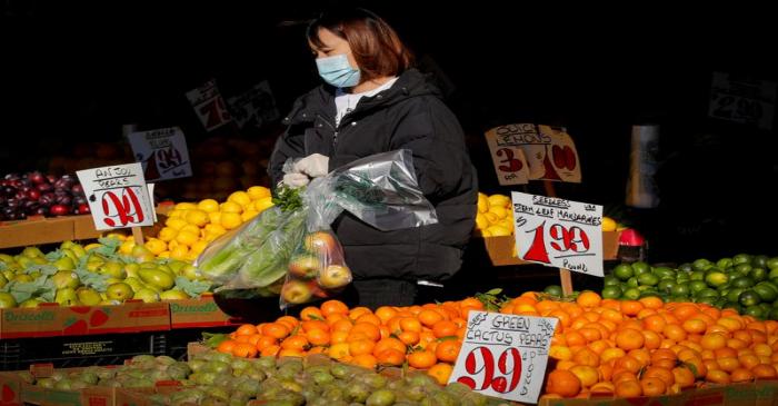 FILE PHOTO: A woman wears a mask and gloves as he shops at a fruit stand, during the outbreak