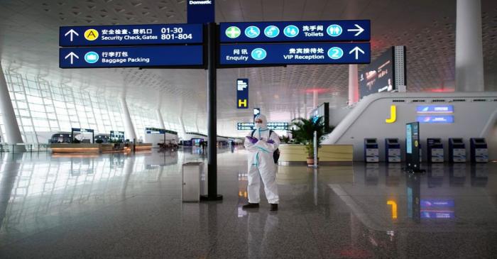 Man in protective suit stands at Wuhan Tianhe International Airport in Wuhan