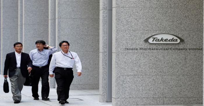 People walk past the new headquarters of Takeda Pharmaceutical Co in Tokyo