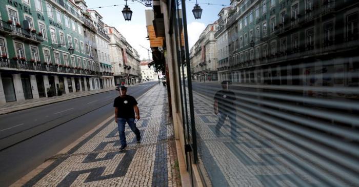 FILE PHOTO: A man walks down a deserted street in Lisbon, Portugal during the coronavirus