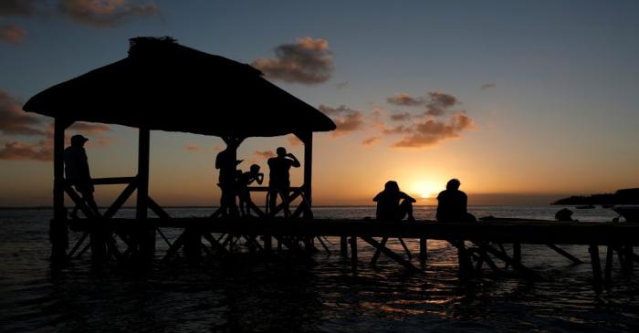 FILE PHOTO: People look at the sunset from the beach in Bel Ombre