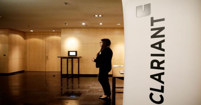 Woman stands next to logo of Swiss specialty chemicals company Clariant ahead of a news
