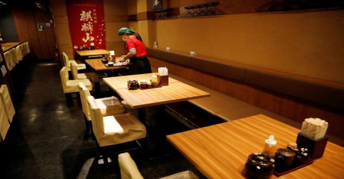 A waitress wearing a protective mask cleans a table at Toshirhin restaurant in Tokyo