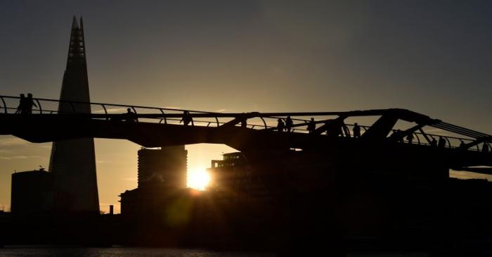 Workers cross the Millenium Bridge during the morning rush hour in the City of London in London