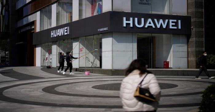 FILE PHOTO: People wearing face masks are seen at a Huawei shop on a street as the country is