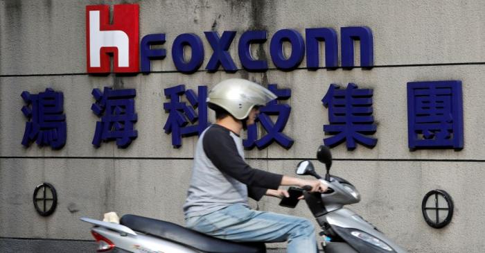 FILE PHOTO: A motorcyclist rides past the logo of Foxconn, the trading name of Hon Hai
