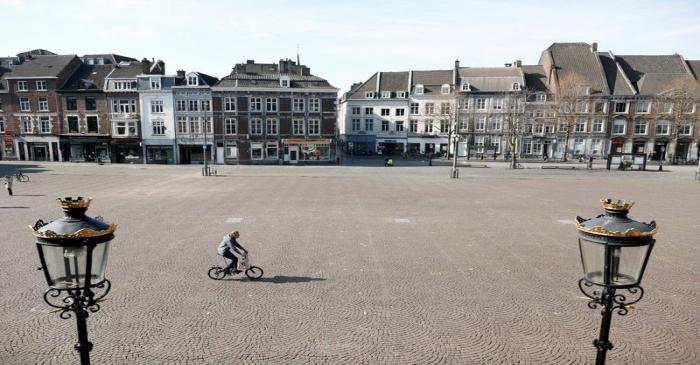 A cyclist crosses an empty square in central Maastricht