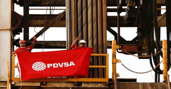 FILE PHOTO: Oilfield workers hold a flag with the corporate logo of Venezuela's state oil