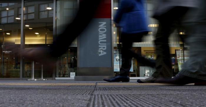 FILE PHOTO: Pedestrians walk past a signboard of Nomura Securities outside its branch in Tokyo