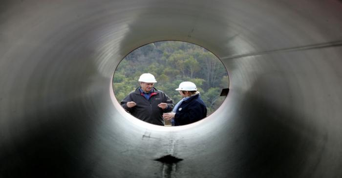 FILE PHOTO: Engineers talk standing next to pipes at a pipeline building site of the Sakhalin-2