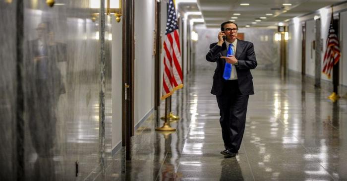 Treasury Secretary Steve Mnuchin takes a phone call in the hall outside a meeting to wrap up