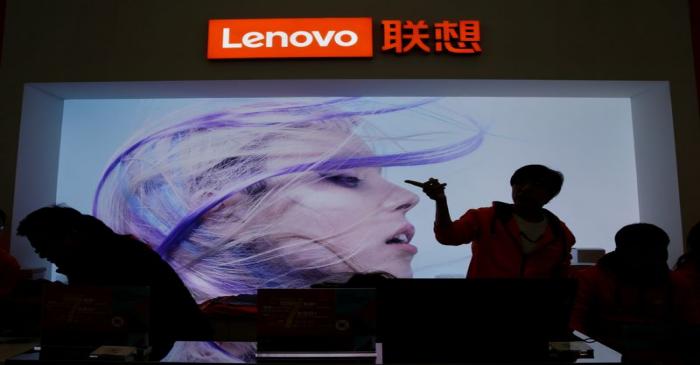 An employee gestures next to a Lenovo logo at Lenovo Tech World in Beijing