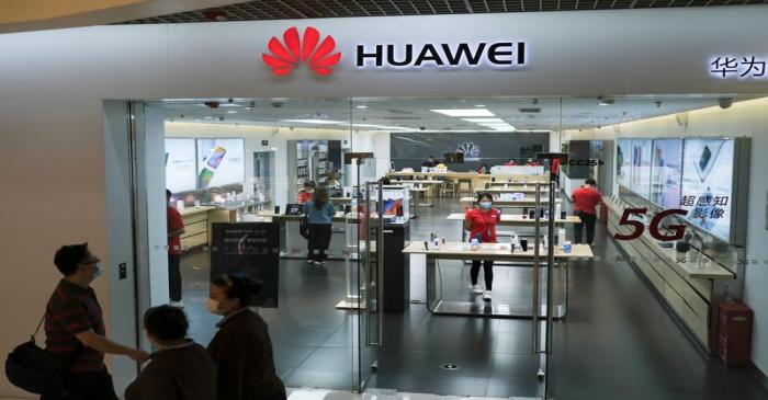 People wearing face masks walk past a?Huawei?store at a shopping mall, following an outbreak of