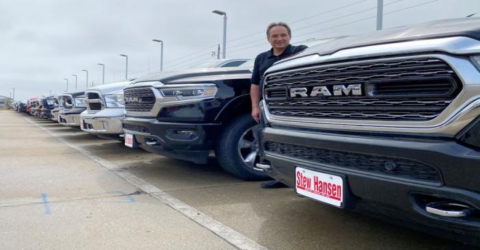 Jerry Bill, general manager of Stew Hansen Chrysler Dodge Jeep Ram, poses among a line of Ram