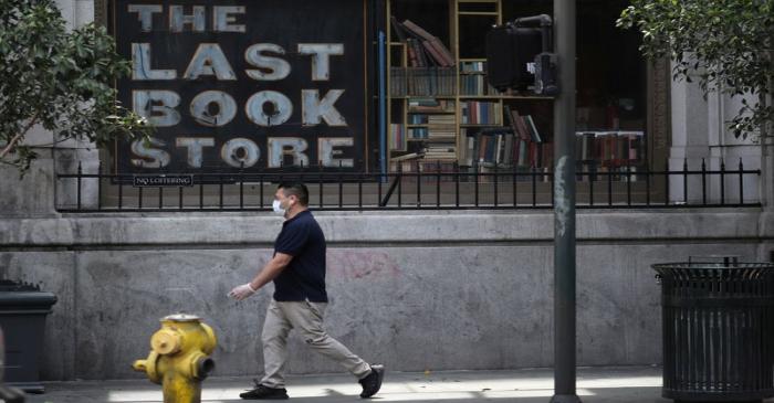 A man walks past a closed bookstore on the first day of the reopening of some businesses in Los