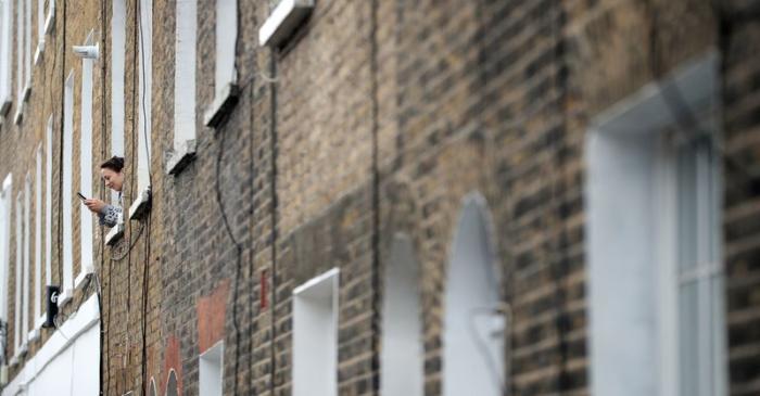 FILE PHOTO: A woman is seen using her phone from a window of a residential house in