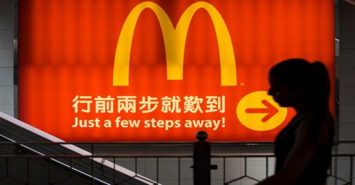 A woman walks past a logo of McDonald's in Hong Kong