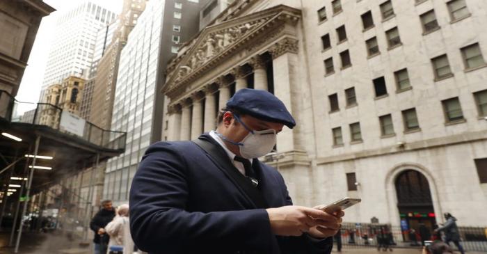 FILE PHOTO: A man wears a protective mask as he walks on Wall Street during the coronavirus