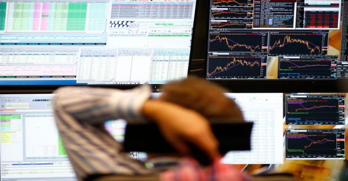 A trader sits in front of the computer screens at his desk at the Frankfurt stock exchange