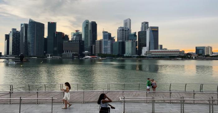 Passers-by hold their mobile phones as people take a selfie photo using a smartphone, with