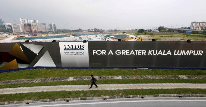 FILE PHOTO: A man walks past a 1 Malaysia Development Berhad (1MDB) billboard at the funds