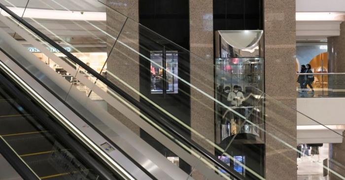 People wearing protective masks ride a lift at Times Square shopping centre, following the