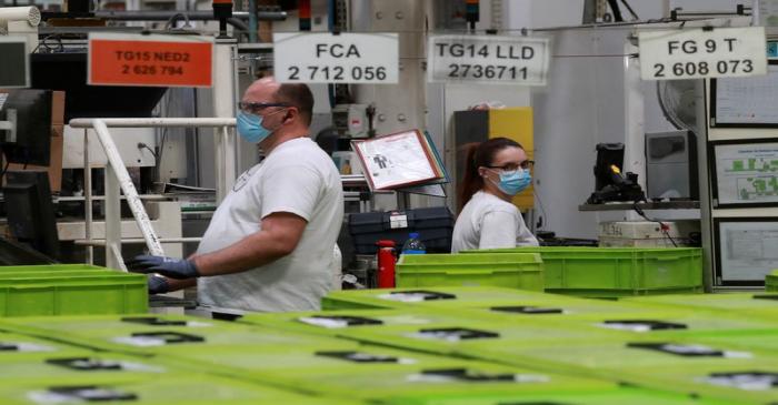 Employees wearing protective face masks work at a factory of manufacturer Valeo, during a visit