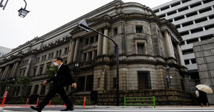 A man wearing a protective mask walks past the headquarters of Bank of Japan amid the