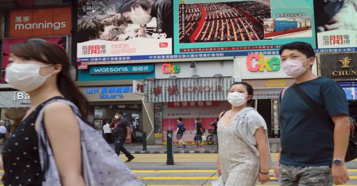 People walk past a TV screen showing the closing session of the National People's Congress