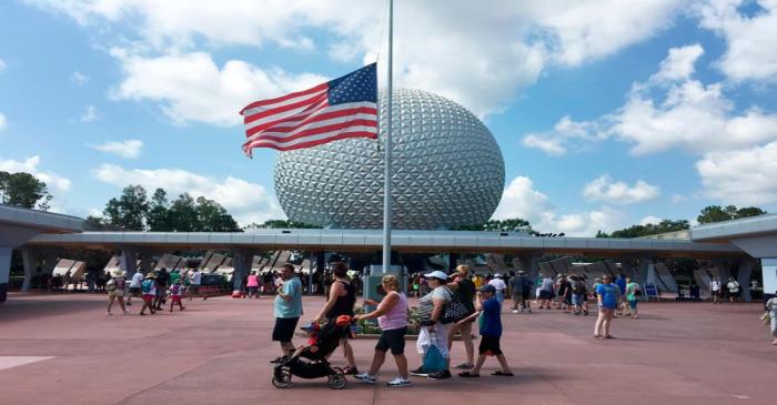 Visitors walk pass a Stars and Stripes flying half-staff at the entrance to the Epcot Center at