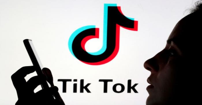 FILE PHOTO: A person holds a smartphone as Tik Tok logo is displayed behind in this picture