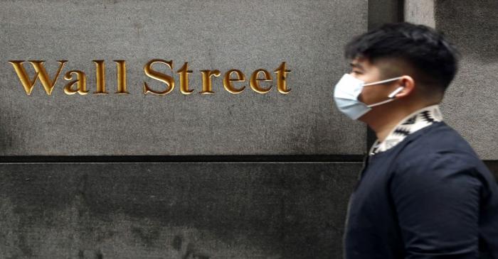 FILE PHOTO: A man wears a protective mask as he walks on Wall Street during the coronavirus