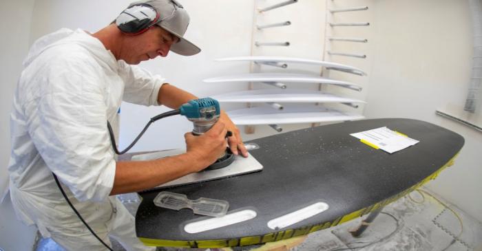 FILE PHOTO: James Black works on a soft INT surfboard at the INT surfboard factory in Carlsbad,