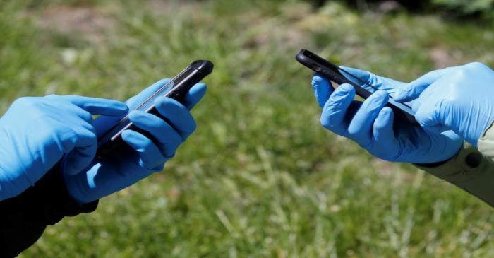 People wearing protective gloves use their smartphones amid the coronavirus disease outbreak in