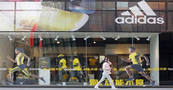 FILE PHOTO: A woman walks past an Adidas shop at a shopping district in Beijing