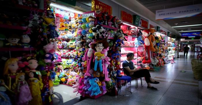 A man sits outside a stall that sells toy products at the Yiwu Wholesale Market following an